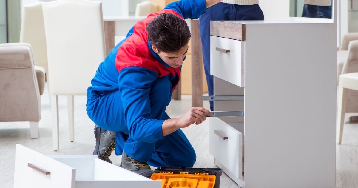 Monteur setzt Ladenschienen in eine Kommode im Wohnzimmer ein